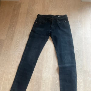 Replay svarta jeansbyxor slim fit - Snygga svarta jeans från Replay med klassisk femficksdesign och diskret Replay-logga på fickan. Jeansen har en slim passform och raka ben, tillverkade i mjukt jeansmaterial med lite stretch för extra komfort. Perfekta för dig som gillar stilrena och bekväma byxor.