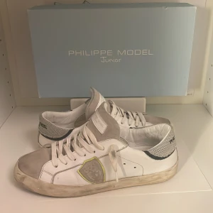 Vita sneakers från Philippe Model - Snygga vita sneakers från Philippe Model med grå detaljer och snörning. Skorna har en stilren design med märkets logga på sidan och hälen. Perfekta för en avslappnad stil.tar emot byten