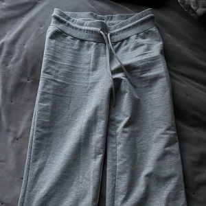 Lågmidjade mjukisbyxor - Säljer ett par bekväma lågmidjade grå mjukisbyxor med snörning i midjan. Perfekta för en avslappnad dag hemma eller skolan. Byxorna har en loose passform och är tillverkade i mjukt material för extra komfort.