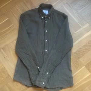 Linneskjorta från Bläck - Helt ny olivgrön linneskjorta från Bläck i en skräddarsydd passform. Skjortan har långa ärmar och knappar framtill. I nyskick! Perfekt för en stilren look. ✅Nypris 899kr! Hör av er vid frågor eller funderingar!