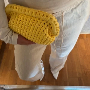 Gul handvirkad clutch / handväska - Säljer en gul handvirkad clutch / handväska som jag har virkat. Väskan är i ett mjukt garn och är väldigt rymlig! Kan bäras i handen som en clutch eller bäras i handtaget.  Kan Även Göra Andra Färger / storlekar💕
