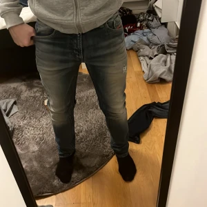 Blå diesel jeans med slitningar  - Säljer ett par blå jeans med snygga slitningar och en klassisk femficksdesign. Jeansen har en normal passform och är perfekta för en avslappnad stil. De har en dragkedja och knapp framtill.