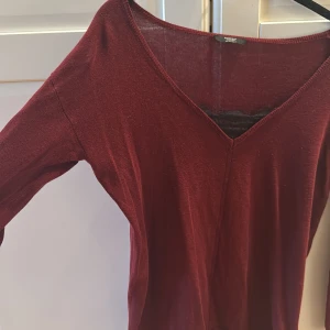 Vinröd tröja från Parfois - Säljer en stilren vinröd tröja från Parfois med v-ringning. Tröjan har långa ärmar och är perfekt för både höst och vinter. Storlek s/m