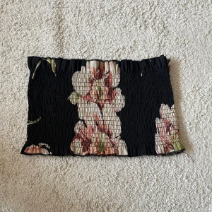 Svart blommig tubtopp - Säljer en svart tubtopp med blommigt mönster i storlek S