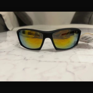 Svarta solglasögon från Future Eyewear - Snygga svarta solglasögon med spegelglas från Future Eyewear. De har en sportig design med rektangulära linser och en bekväm passform. Perfekta för soliga dagar och utomhusaktiviteter.