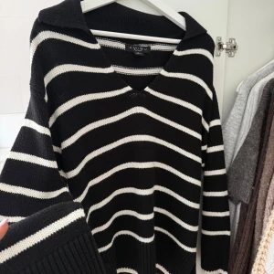 Svart och vit randig tröja  - Säljer en snygg svart och vit randig tröja från med v-ringning och långa ärmar. Perfekt för en stilren look. Tröjan har ribbade muddar vid ärmslut och nederkant.