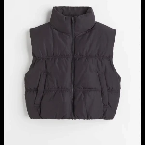 Svart dunväst med dragkedja - Snygg svart dunväst med dragkedja framtill. Västen har en hög krage och två fickor på sidorna. Perfekt för lager-på-lager under kyligare dagar.