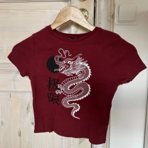 Vinröd topp - Säljer en cool vinröd topp från New Yorker med ett stort vitt draktryck på framsidan. 