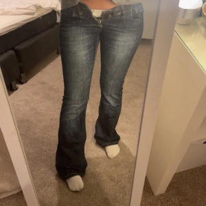 Blå bootcut jeans - Snygga blå bootcut jeans med en klassisk femficksdesign och knappgylf. Knappen är med en tofs tyvärr men de syns ej när man knäpper. De är försmå på mig därför jag ej kan knäppa men de funkar och de är skitsnygga!! De är gammal modell men de står 36/32 alltså storlek 36