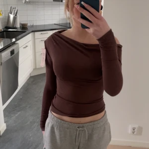 Brun offshoulder topp från Nelly - Säljer en snygg brun offshoulder topp från Nelly. Toppen har en tight passform och långa ärmar, perfekt för en stilren look. Materialet är mjukt och bekvämt, vilket gör den idealisk för både vardag och fest. Hör av dig vid intresse!