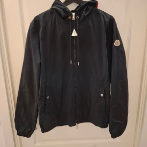 Moncler Vindjacka - Moncler vindjacka i storlek L men passar även M, svart, använd fåtal gånger så den är i bra skick, påse ingår, kom privat för fler frågor
