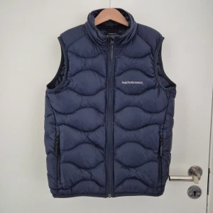 Mörkblå dunväst från Peak Performance - Säljer en riktigt snygg tunn mörkblå dunväst från Peak Performance i väldigt bra skick. Den är perfekt att ha nu till våren då jackor börjar att bli för varmt. Västen är storlek 150 men passar för de mellan 150-160cm. Nypris 1 400kr. Pris är diskuterbart vid snabb affär. Skriv om du har några funderingar.