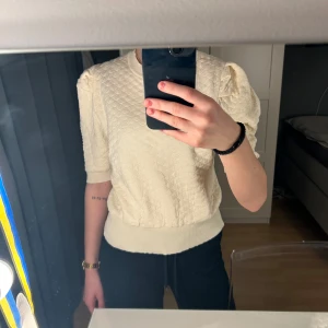 Gulaktig tröja från Knit Mix - Säljer en gulaktig tröja från Knit Mix. Tröjan har ett quiltat mönster och korta ärmar. Perfekt för en elegant och bekväm look. Passar bra till både jeans och kjol.💞