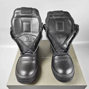 Svarta sneakers med hög plös - Snygga svarta sneakers från Rick Owens med en unik design. Skorna har en hög plös och snörning som ger en cool look. Tillverkade i skinn för en lyxig känsla. Perfekta för dig som vill sticka ut med stil.