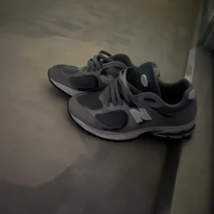 New Balance skor - Snygga grå sneakers från New Balance med vit sula och klassisk snörning. Perfekta för både vardag och träning. De har en bekväm passform och är designade för att ge bra stöd och komfort. Använda ett par gånger max. Kom med bud svarar inget under 1000kr & Byter även!