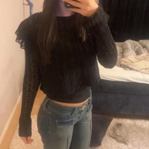 Svart spetsblus - Säljer en elegant svart blus med spetsdetaljer och långa ärmar. Blusen har en lös passform och är perfekt för en stilren look. Den är croppad och har volangdetaljer vid axlarna. Nypris 499kr från zara. Säljer då den inte kommer till användning längre. 