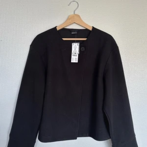 Svart kappa från Gina Tricot - Snygg svart kappa från Gina Tricot med en enkel knapp framtill. Jackan är helt ny med prislappen på. Hör av er🌸