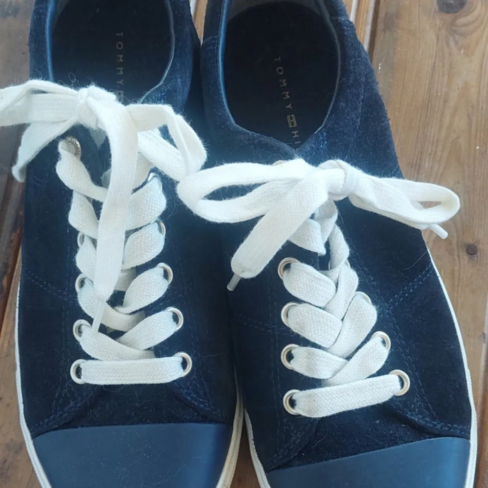 Snygga blå sneakers från Tommy Hilfiger med vita snören och en diskret logga på hälen. Skorna har en klassisk design med rund tå och är perfekta för en avslappnad stil.. Kengät.