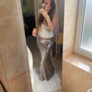 Glansig långkjol - Snygg och elegant glansig långkjol. Kjolen har en smickrande passform och är perfekt för festliga tillfällen. Den är tillverkad i ett material som ger en lyxig känsla och faller vackert längs kroppen.