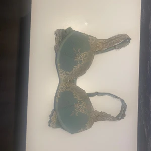 Grön spets-bh från Intimissimi - Supersnygg grön bh från Intimissimi med beige spetsdetaljer och vadderade kupor. Axelbanden är dekorerade med spets och bh:n har klassisk knäppning bak