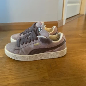  Puma sneakers  - Snygga Puma sneakers i ljusbrun mocka med mörkbruna detaljer och breda snören. Klassisk siluett med vit sula och guldfärgad Puma-logga på sidan. Perfekta för dig som gillar en stilren och avslappnad look.