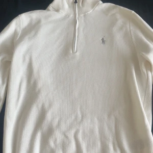 Vit half zip tröja från Ralph Lauren - Helt oanvänd Vit långärmad tröja från Ralph Lauren med half zip och broderad logga på bröstet. Tröjan har en klassisk passform och är tillverkad i mjuk bomull, perfekt för lager-på-lager. Enkel och stilren design som funkar till det mesta. 