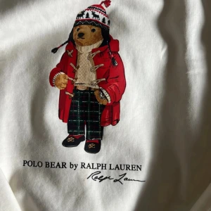Vit Polo Bear sweatshirt från Ralph Lauren - Vit sweatshirt från Ralph Lauren med ikoniska Polo Bear-trycket framtill. Tröjan har rund halsringning och långa ärmar. Klassisk och stilren look, nypris 1800