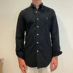 Svart Ralph Lauren Skjorta - Svart Ralph lauren skjorta || Storlek XS || Skjortan är i bra skick || Mitt pris 599kr || Modellen på bilden är 170cm och väger 62kg || Tveka inte på att höra av dig vid frågor eller funderingar 