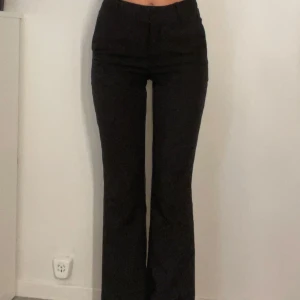 Svarta bootcut kostymbyxor - Snygga svarta kostymbyxor med bootcut passform och hög midja. Byxorna har klassiska fickor bak och bälteshällor i midjan. Perfekta för en clean och stilren look, passar till allt från sneakers till klackar.