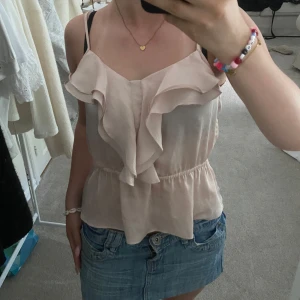 Ljusrosa volangtop från H&M - Supersöt ljusrosa linnetopp från H&M med volangdetaljer framtill och smala axelband som knyts upptill. Den är i storlek 36. Skriv om ni undrar nått mer!❤️