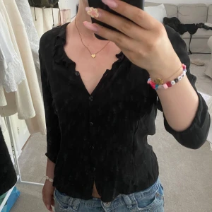 Blus - Supersnygg svart blus i 100% silke från Ann Taylor. Blusen har v-ringning med volangkant, knappar framtill och trekvartsärm. Skriv om ni funderar över något!