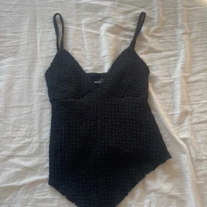 Svart bikiniöverdel från Gina Tricot XS - Supersnygg svart linne från Gina Tricot i storlek XS. Modellen har smala axelband  och en texturerad, ribbad yta. Har själv sytt upp axelbanden då de var för långa för mig. 