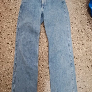 Weekday Rowe extra high straight jeans - Säljer ett par ljusblå Weekday Rowe jeans i modellen extra high straight. Jeansen har riktigt hög midja och raka ben, klassisk femficksdesign och är gjorda i bomull. Perfekta för dig som gillar en clean och tidlös look.