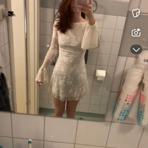 Vit blommig kortklänning med öppen rygg - Supersöt vit kortklänning med blommigt mönster från hello molly, långa trumpetärmar och öppen rygg med knyt. Klänningen har en figurnära passform upptill och utsvängd kjol. Perfekt för sommarens alla tillfällen! Använd en gång, nypris 1350. Säljer då den inte kommer till användning 