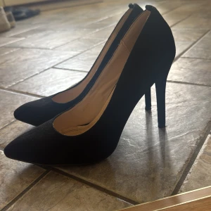 Svarta pumps med spetsig tå och klack - Stilrena svarta pumps från Högl med spetsig tå och hög klack. Skorna är i mocka och har en klassisk siluett som ger en elegant look. Perfekta för dig som vill ha en tidlös och snygg sko med lite edge.