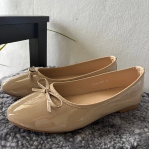 Beige ballerinaskor med rosett - Snygga beige ballerinaskor i glansigt syntetmaterial med rosettdetalj framtill☺️ Helt nya och enbart testade. Säljer då de tyvärr är för små🥲