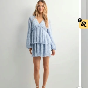 Ljusblå blommig kortklänning - Supersöt ljusblå kortklänning med blommigt mönster och v-ringning. Aldrig använd och prislappen är kvar 💙 