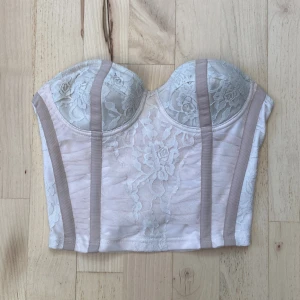 Vit korsettopp - Superfin vit korsett med spets och vadderade kupor. Baksidan har hysk- och hakknäppning för justerbar passform. 