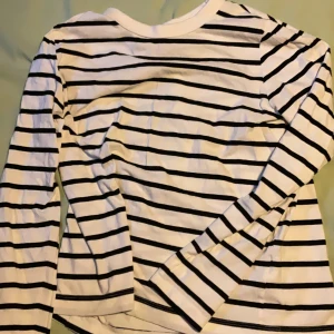 Randig långärmad tröja från H&M - Vit och svart randig långärmad tröja från H&M i storlek S. Klassisk och enkel design med rund halsringning, perfekt att styla med jeans eller kjol. Tillverkad i mjuk bomull som känns skön mot huden.