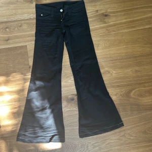 Svarta bootcut jeans från Weekday - Säljer ett par svarta jeans från Weekday med klassisk bootcut-passform. Byxorna har fem fickor, normal midja och är tillverkade i ett stretchigt jeanstyg som sitter snyggt över höfterna och släpper ut över benen. Perfekta för dig som gillar retrovibbar.