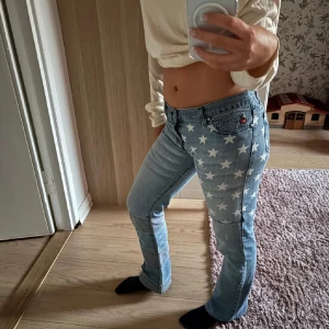 Miss sixty jeans med stjärnmönster - Snygga ljusblå jeans med ett coolt stjärnmönster på benen. De har en lågmidjad passform och en bootcut-stil. Perfekta för att sticka ut med en unik look. 🌟Midjemått: 38cm                                                              Innerbenslängd: 73cm
