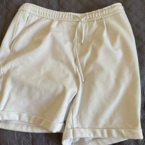 Vita shorts med snörning från Zara - Snygga vita shorts från Zara i storlek L. De har elastisk midja med snörning, fickor fram och bak samt uppvikta benslut. Perfekta för varma dagar och chill vibes. Materialet känns mjukt och skönt mot huden.