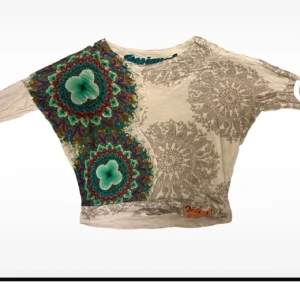 Desigual - Unik långärmad topp från Desigual med färgstarka mandala-inspirerade mönster i turkos, rött och lila på ena sidan och grått spetsliknande tryck på andra. Oversize o wideneck, passar S-L beroende på hur man vill ha passformen. Klassisk Desigual i bra skick.