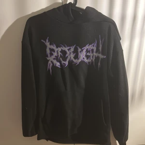 Svart hoodie med lila tryck - Svart fleece hoodie  med stor luva och ett fett grafiskt tryck, använts ca 3 gånger från newyorker i loose fit. 