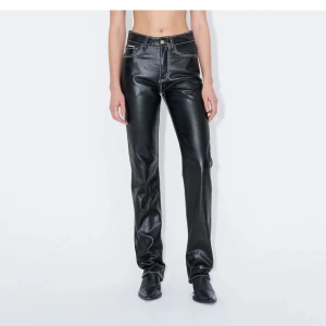 Svarta raka byxor i skinnlook - Snygga svarta byxor i skinnimitation med raka ben och kontrasterande vita sömmar. Klassisk femficksmodell med låg midja och coola detaljer på bakfickorna. Helt oanvända med lappen kvar. Nypris 3600:-