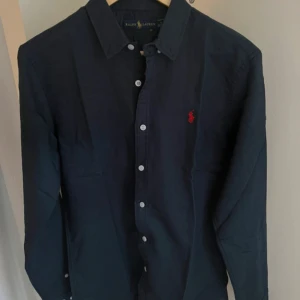Mörkblå skjorta från Ralph Lauren - Säljer nu denna riktigt snygga linne skjortan från Ralph Lauren som är perfekt nu inför sommaren. Aldrig använd bara testad. priset är ej hugget i sten så kom med prisförslag!