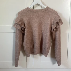 Beige stickad tröja med volang H&M - Superfin beige stickad tröja från H&M med volangdetaljer på axlarna. Tröjan har lång ärm och en klassisk rund halsringning. Använd några  gånger men köpt för över ett år sedan💓 
