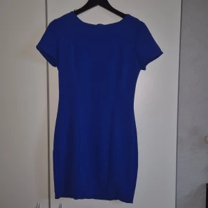 Kornblå kortklänning från Forever 21 - Snygg kornblå kortklänning från Forever 21 med rund halsringning och korta ärmar. Klänningen har en figurnära passform och är tillverkad med 95% polyester och 5% elastan. BRA SKICK BORTSETT FRÅN: Behövs lagning på höger ärm där sömmen släppt (inget jag kan eller orkar) så hoppas den kan få ett fint liv hos någon annan som kan laga! Inköpt i Australien, anser att storleken sitter mer som S än M.  Dragkedja i ryggen. 