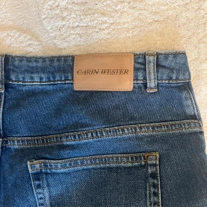 Blå jeans från Carin Wester - Snygga blå jeans från Carin Wester i mörk tvätt. Jeansen har raka ben och är tillverkade i mjukt denimtyg. Passformen är perfekt för någon som är kortare. Strl lapp saknas men sitter som 34-36.