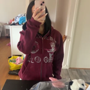 Aim for the moon hoodie - Säljer en zip hoodie med dragkedja och huva. Framsidan har stora strasstenar i silver och rosa som bildar texten 'AIM FOR THE MOON' och motiv av en tecknad figur och måne. Jackan har känguruficka och är i mjukt bomullsmaterial. Perfekt statement-plagg för dig som gillar unika detaljer. Oanvänd! Endast testad, säljer för har ej användning för den vill bara bli av med den. Priset kan diskuteras💓💓